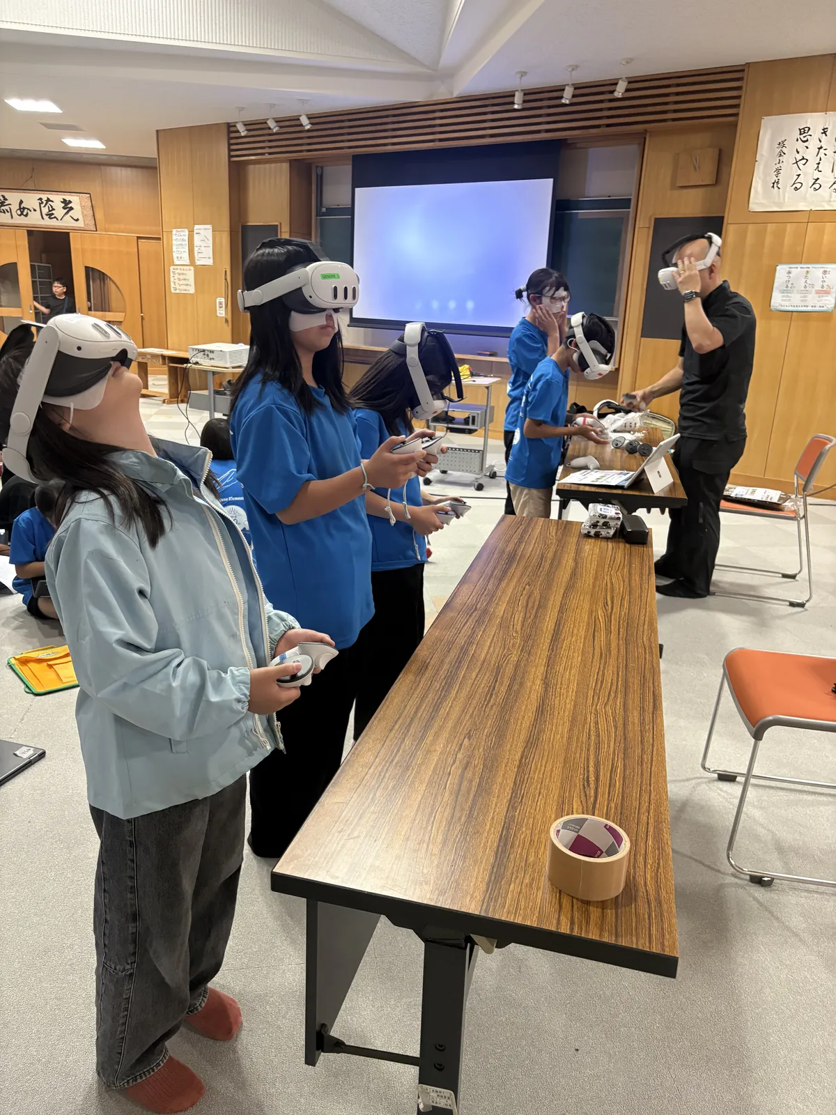 VRゴーグルを着けて立つ児童たちと、案内するスタッフ